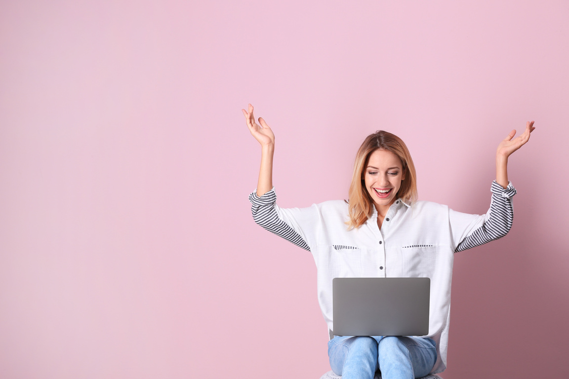 Cheerful Young Woman with Laptop against Pink Background